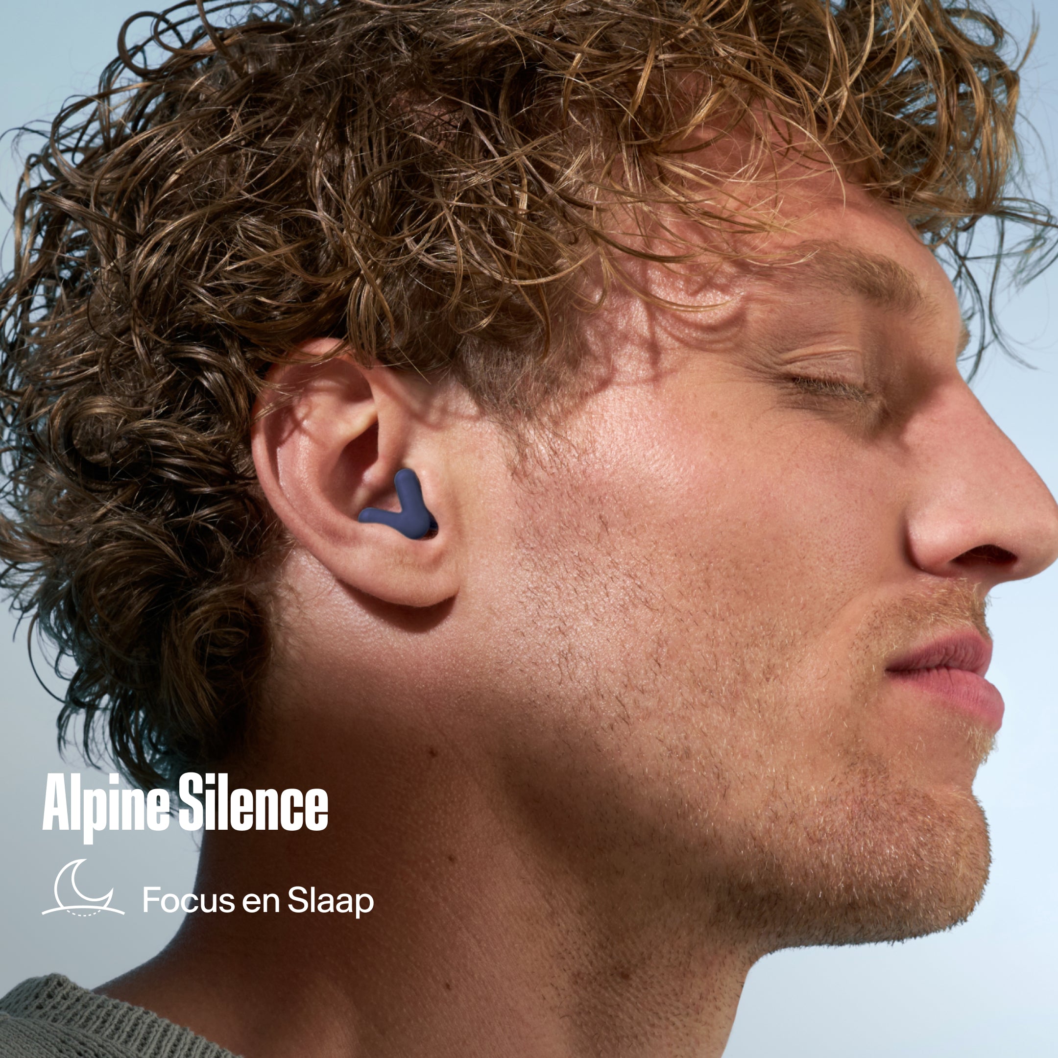 Alpine Silence oordopje in het oor van een man met krullend haar, met de tekst &