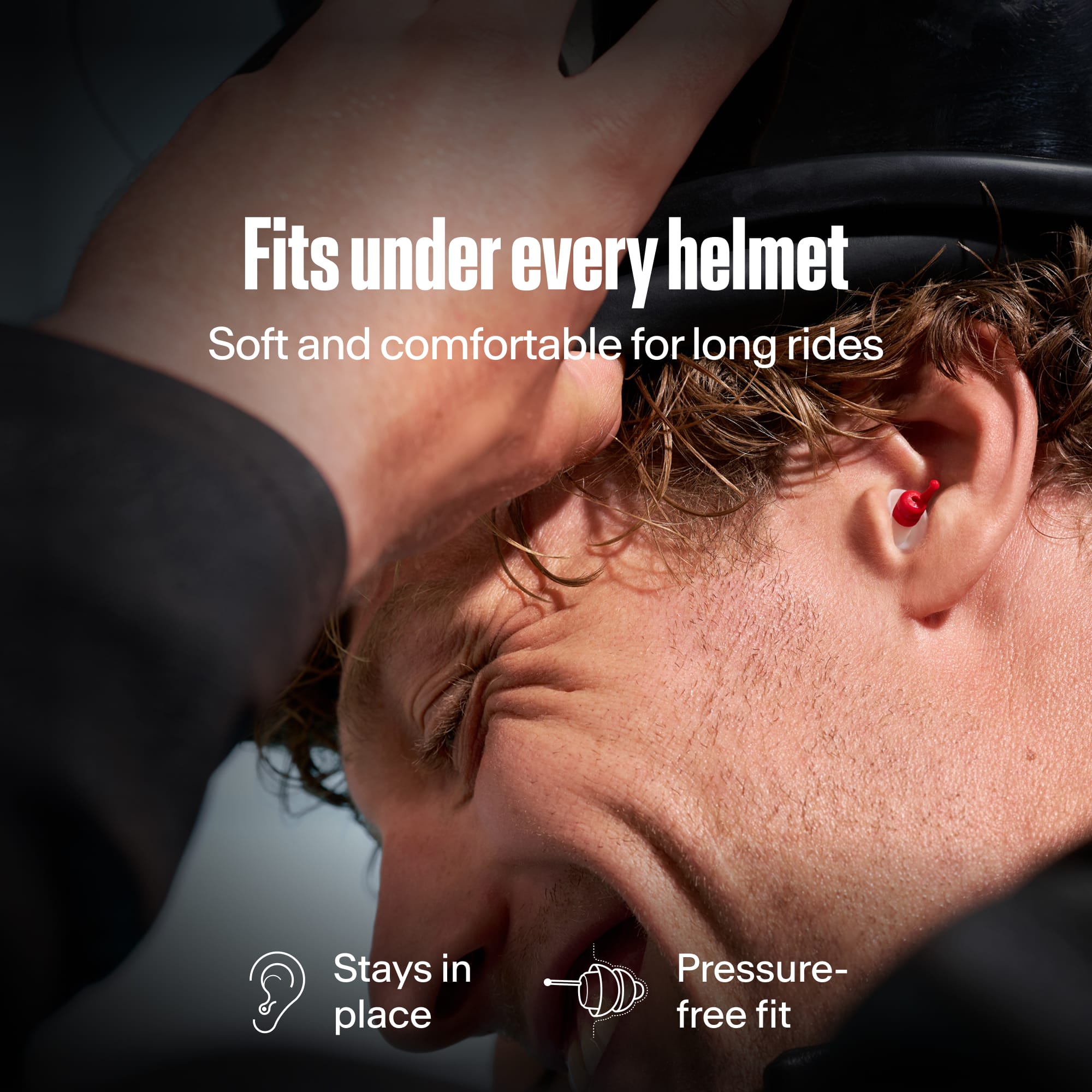 Motorcyclist wearing an Alpine MotoSafe Sport earplug while putting on a helmet, with the text &